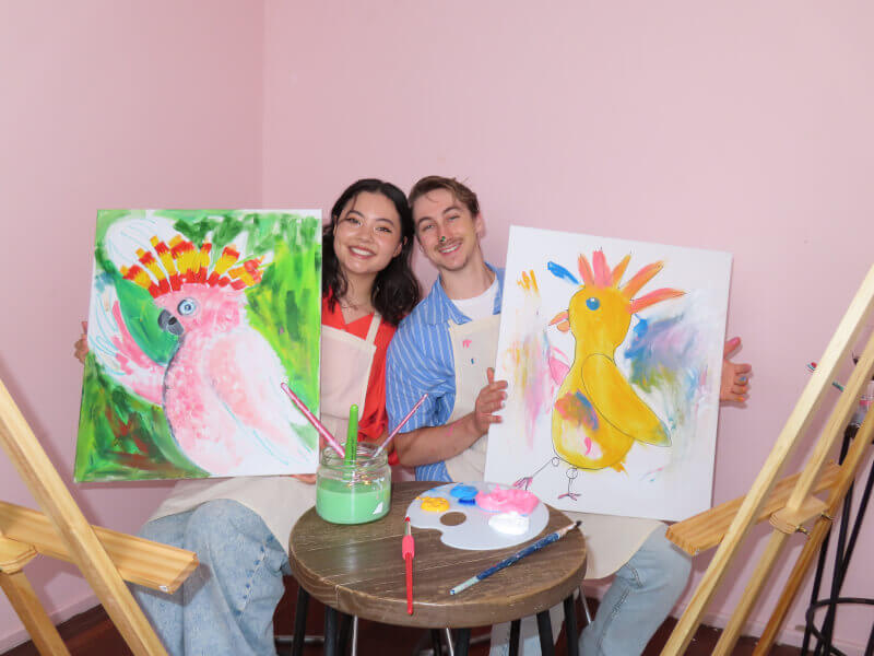 Couple holding up finished paintings